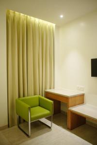 a green chair in a room with a desk at Hotel Rancehok's Mathura in Gokul +22 photos