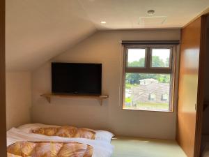 a bedroom with a flat screen tv and a bed at Royal Hotel Kawaguchiko in Fujikawaguchiko
