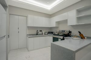 a white kitchen with white cabinets and a sink at Layali Properties - Boho Oasis 3BR Apt - Convention and Exhibition Center in Riyadh