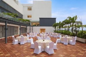 an outdoor patio with white tables and white chairs at Marriott Executive Apartments Hyderabad in Hyderabad