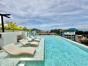 a pool on the roof of a building with lounge chairs at ECOndo Bangsaray in Bang Sare