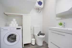 a white bathroom with a washing machine and a toilet at Casa Judit in Los Silos
