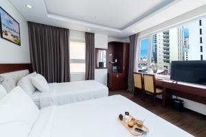 una camera d'albergo con due letti e una scrivania di Dao Ngoc Hotel Da Nang a Da Nang