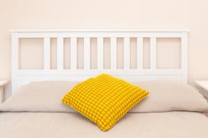 Una cama blanca con una almohada amarilla. en Relax Porto Mannu, en Palau