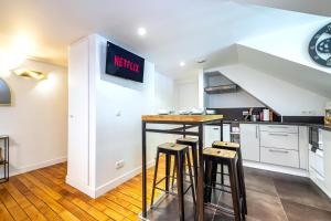 a kitchen with a counter and some stools in it at La Tanière du Roi - Versailles - à 10 min du Château et de la gare in Versailles