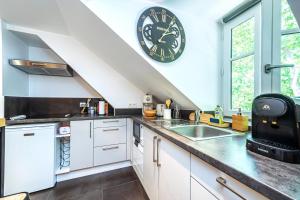 a kitchen with a large clock on the wall at La Tanière du Roi - Versailles - à 10 min du Château et de la gare in Versailles