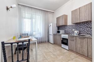 a kitchen with a table and a white refrigerator at Apartments EXPO Residence in Taldykolʼ