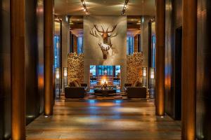Un vestíbulo con chimenea y una cabeza de ciervo en la pared. en The Chedi Andermatt, en Andermatt