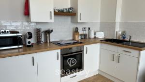 a kitchen with white cabinets and a black oven at Beach Lookout - Direct Beach Access - No Guest Fee in Kent +36 photos