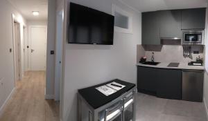 a kitchen with black cabinets and a flat screen tv at AturCangas in Cangas de Onís