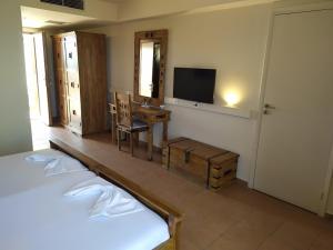 a room with a bedroom with a desk and a television at Simosmare Resort in Elafonisos