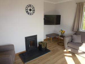 a living room with a fireplace and a clock on the wall at Briardene Cottage - Devon countryside - sleeps 6 in Exeter