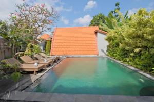 a swimming pool with chairs and an orange roof at Sandat Bali Villa Canggu in Canggu