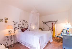 a bedroom with a white bed with a canopy at Santolìo Country Retreat - Relax in Masseria Siciliana con Giardino e Vista in Palazzolo Acreide