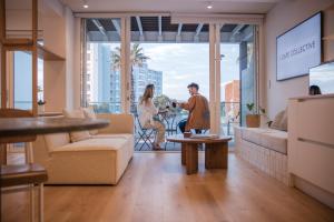 a man and woman in a living room with a view of a city at Seaside 8 l Aparthotel 50m from the Promenade in Cape Town