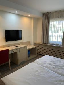 a bedroom with a bed and a desk with a television at Konaci Andjela Apartmani broj 108 in Kopaonik