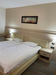 a bedroom with a white bed and a picture on the wall at Konaci Andjela Apartmani broj 108 in Kopaonik