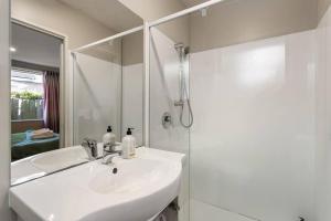 a white bathroom with a sink and a shower at Handy Riccarton Hagley Park CBD 10 Mins in Addington +14 photos