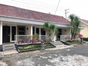 a house with palm trees and a white fence at Selorejo Resort Mitra RedDoorz in Sekar