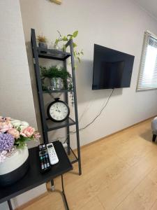 a room with a shelf with a clock and a tv at 新小岩デメテル303 in Tokyo