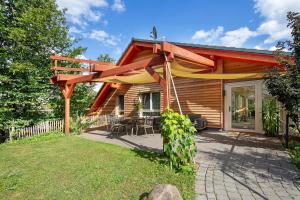 a wooden house with a pergola next to a yard at Leben am Weinberg in Herbstein
