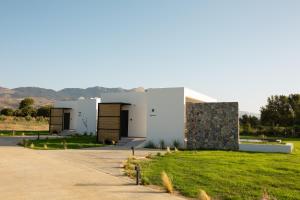 a building with two doors and a grass yard at Aphrodite Luxury Villas & Suites-Private Heated Pool & Jacuzzi in Kos