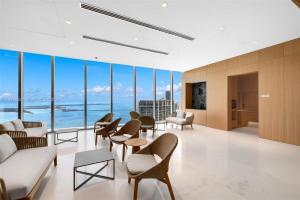 a waiting room with chairs and tables and large windows at ASTON MARTIN TOWER Miami in Miami