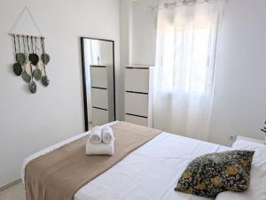 a white bedroom with a bed with towels on it at IslaOC Apartamentos - Apartamento 2 habitaciones primera línea Playa Central Isla Cristina in Isla Cristina