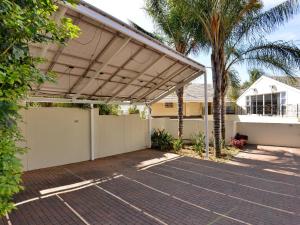 Un garaje con toldo en una casa con palmera. en Atholl Guest House, en Johannesburgo