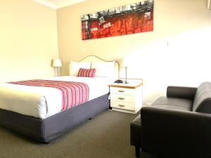 a bedroom with a bed and a chair and a couch at Golfview Motor Inn in Wagga Wagga