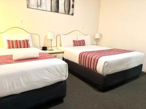 two beds sitting next to each other in a room at Golfview Motor Inn in Wagga Wagga