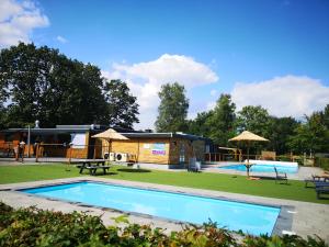 a swimming pool with a playground and a building at Chalet Hemelriekje in Gasselte