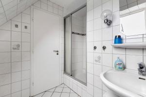 a white bathroom with a sink and a shower at Ferienwohnung I Raup in Winnert +17 photos