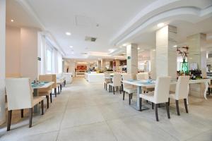 a dining room with tables and white chairs at AluaSun Continental Park Hotel & Apartments in Playa de Muro
