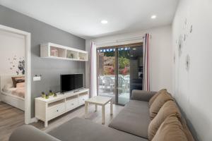Una sala de estar con un sofá y un televisor. en Apto Jardin del Sol Beach, en Puerto de Santiago