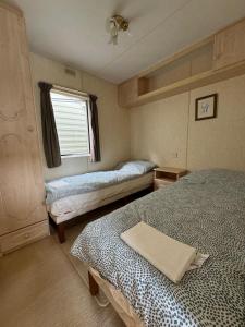 a small bedroom with two beds and a window at Helove Domki Karoliny in Hel