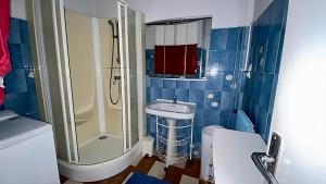 La salle de bains est pourvue de carrelage bleu, d'une douche et d'un lavabo. dans l'établissement IDEAL Plein Centre - 65m2- Piscine et Garage, à Perpignan 17 autres photos