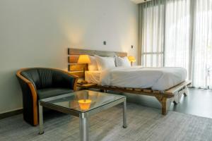 1 dormitorio con cama, silla y mesa de centro en BISABO SUITES APARTMENT LTD, en Kigali 18 fotos más