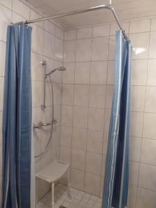 a bathroom with a shower with a bench and a shower curtain at Barrierefreie Ferienwohnung in Borkum