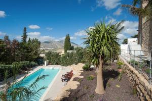 a swimming pool with a palm tree next to a building at Baglio Maranzano - Marietta in Buseto Palizzolo