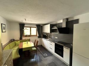 a kitchen with a table and a green couch in it at Apartement Schuster Lake Prags Braies in Braies