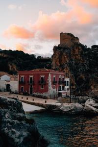 a red and white building next to the water at Tonnara di Scopello in Castellammare del Golfo