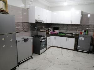 une cuisine avec des appareils en acier inoxydable et des armoires blanches dans l'établissement Appartement pour famille, à Agadir
