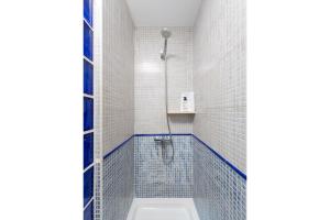 un bagno con doccia con piastrelle blu e bianche di San Isidoro Cathedral Suite by Valcambre a Siviglia