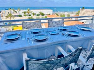 a blue table with plates and glasses and the ocean at La casa de la playa in Piles