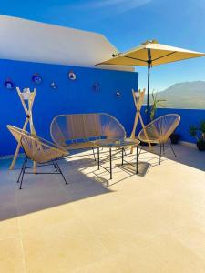 due sedie e un tavolo e un ombrellone su un patio di Appartement luxe Perle Des Montagnes Chechaouen a Chefchaouen