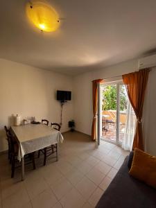 sala de estar con mesa y puerta corredera de cristal en Čudina Beach Apartments, en Pakoštane