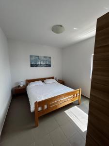 Un dormitorio con una cama de madera en una habitación. en Čudina Beach Apartments, en Pakoštane