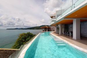a swimming pool on the side of a building next to the water at Cape Sienna Villa 4 - A Waterfront Grand Oasis in Kamala Beach