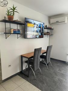 a dining room with a table and chairs and a tv at Bellas apartmani in Novi Sad